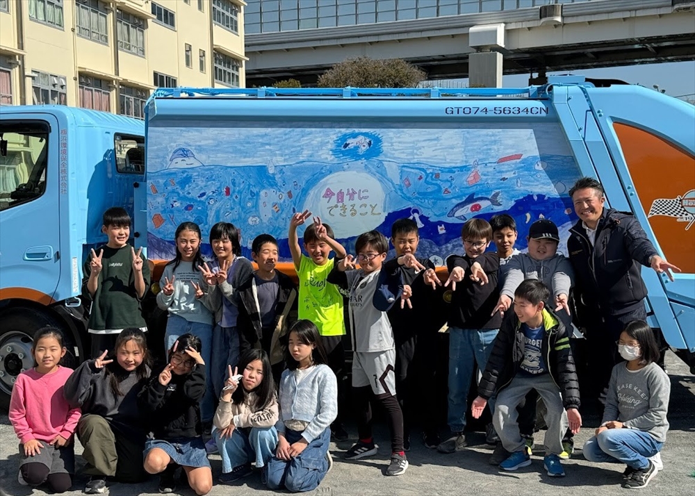 横浜市の小学校で　デザインパッカー車お披露目　横浜環境保全 ４年生全員で制作_完成したデザインパッカー車の前に並ぶ生徒たちと髙橋社長（後列右端）