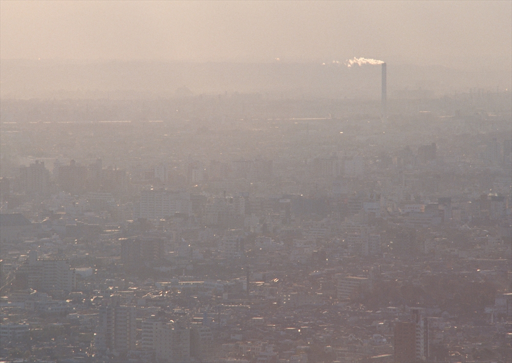 IMAGE_この写真は都市の風景を捉えているようです。遠くの煙突からは煙が上がっており、全体的に曇りや煙のようなものに包まれている印象があります。具体的な場所や詳細は分かりませんが、都市的な環境を反映していると思われます。