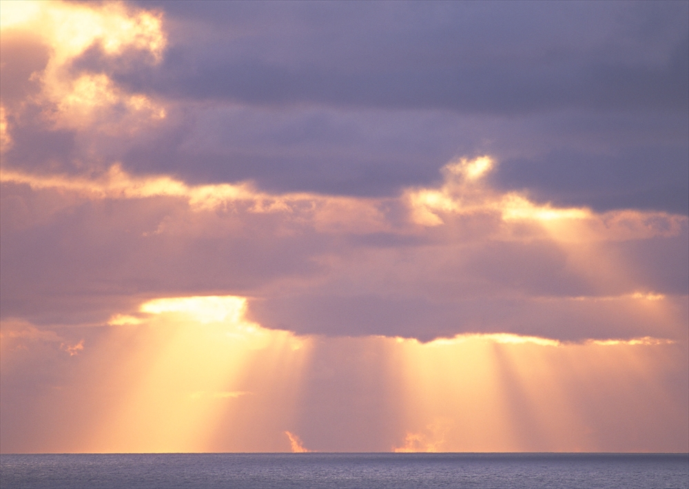 IMAGE_この写真は、空と海の景色を捉えたもので、雲間から太陽の光が差し込んでいる様子が見えます。特に、晴れた日の夕方や朝の時間帯に見られる美しい自然の光景を思わせるものです。