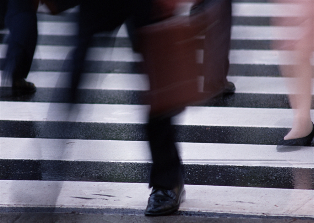 IMAGE_これは横断歩道を渡っている人々の写真のようです。動きがあるため、人物が流れるような印象を与えています。おそらく都市の風景の一部です。