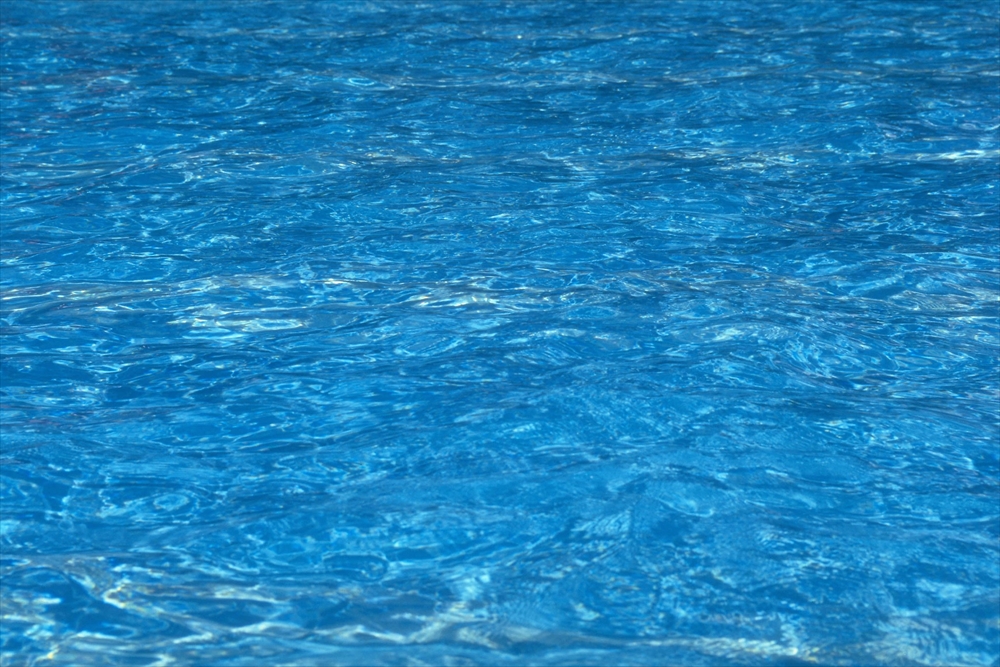 IMAGE_これは水面の写真で、透明な青い水が映っています。おそらくプールや海の水面を撮影したものと思われます。
