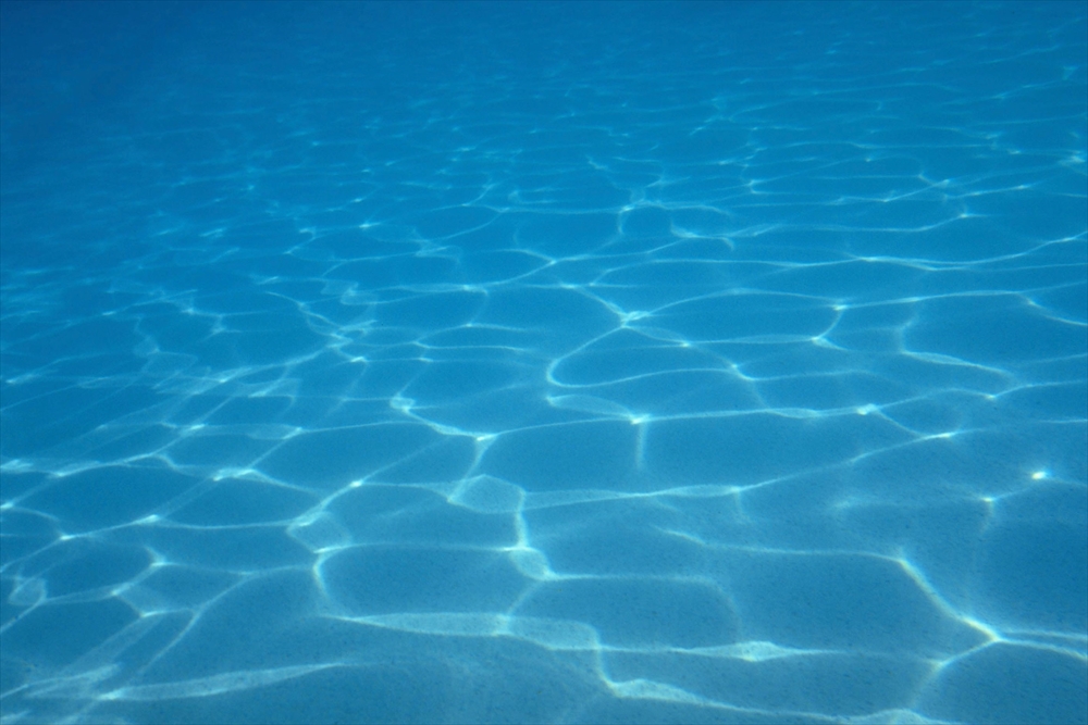 IMAGE_これは水中の写真で、青い水面が映っています。水の表面に光が反射して、波紋が見える様子が印象的です。おそらく海やプールの中の風景だと思われます。