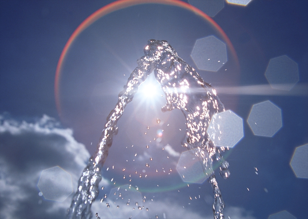 IMAGE_これは水が空中に噴き上がっている写真のようです。背景には青空と雲が見え、光が水面で反射してきれいなエフェクトを作り出しています。全体的にさわやかで明るい印象を与える画像です。