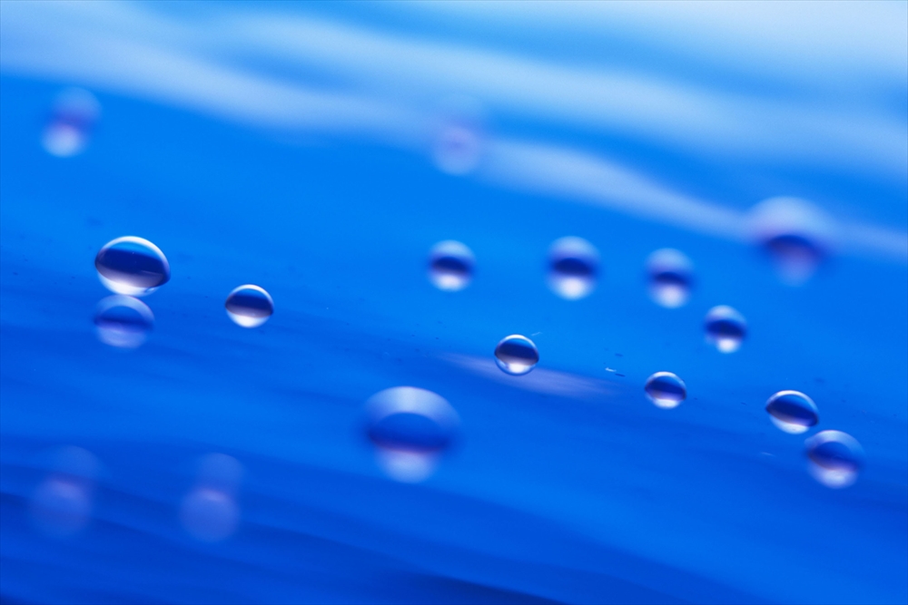 IMAGE_これは水滴が青い背景の上に見える写真です。水滴の形や反射が強調され、きれいな視覚効果を持っています。