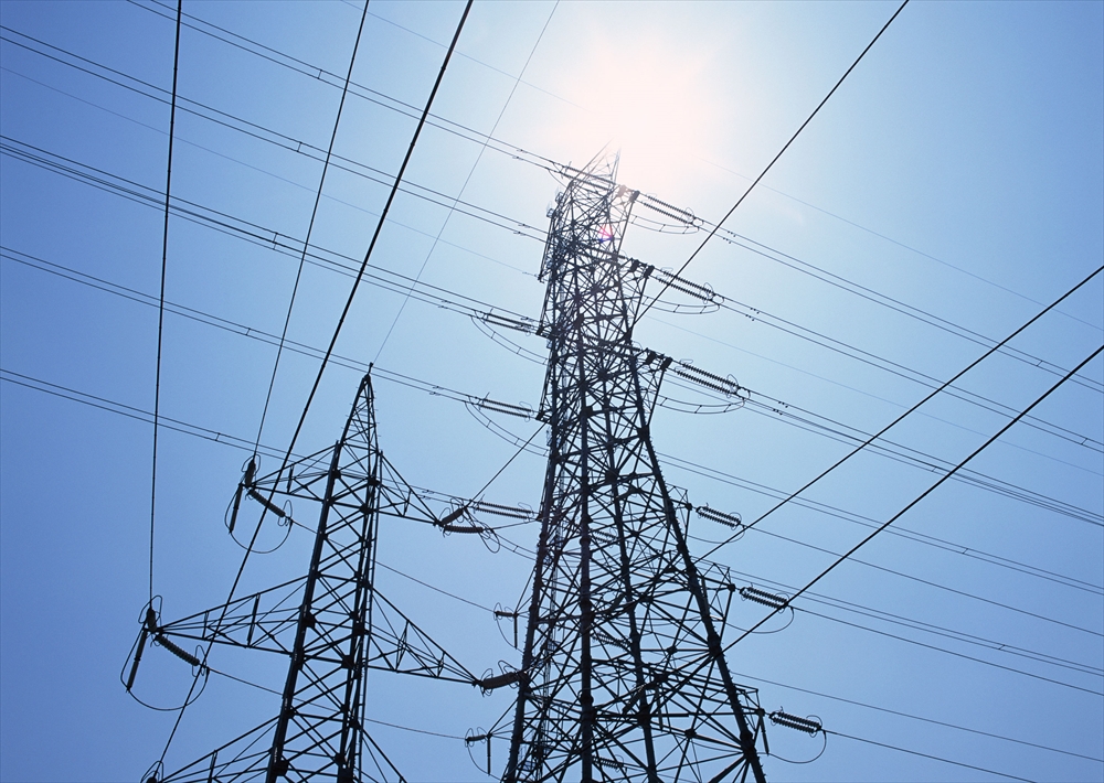 IMAGE_この写真は、電力設備、特に電線と送電塔の写真です。青空の下で、送電線が交差している様子が写っています。これは電力の送水や供給に関する設備を表しています。