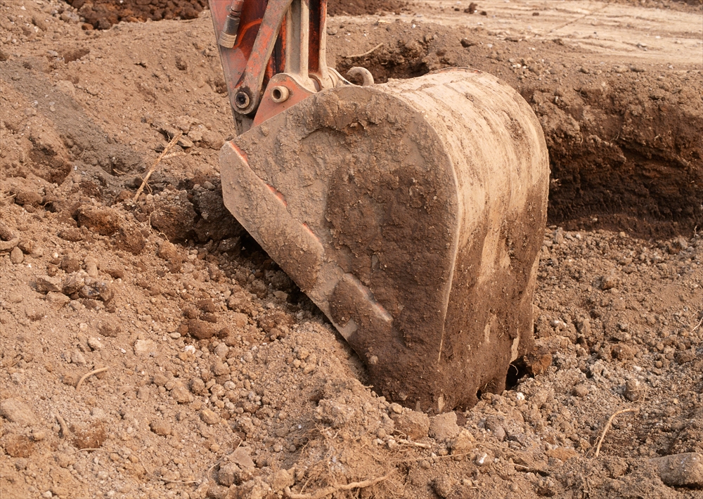 IMAGE_この写真は、土を掘るための重機のバケット（装置の一部）が土の中に入っている様子を捉えたものです。建設現場や土木作業でよく見られるシーンです。