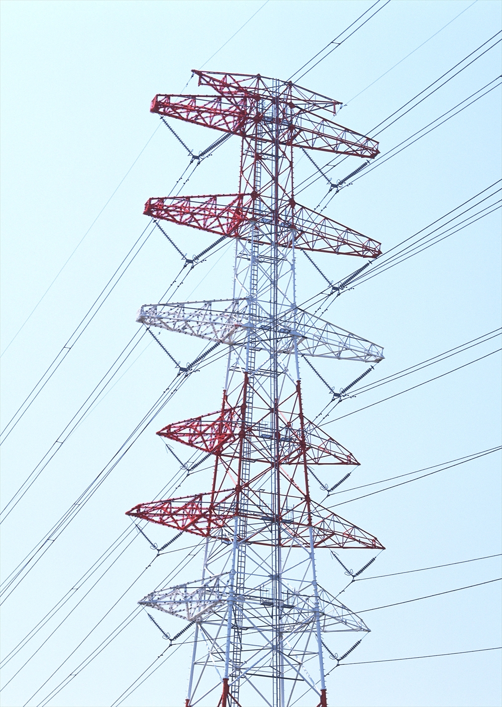 IMAGE_これは送電線の鉄塔の写真です。鉄塔は電力を送るための電線を支える構造物で、通常は高い位置に設置されています。この写真では、赤と白の塗装が施された鉄塔が電線を支えている様子が見られます。