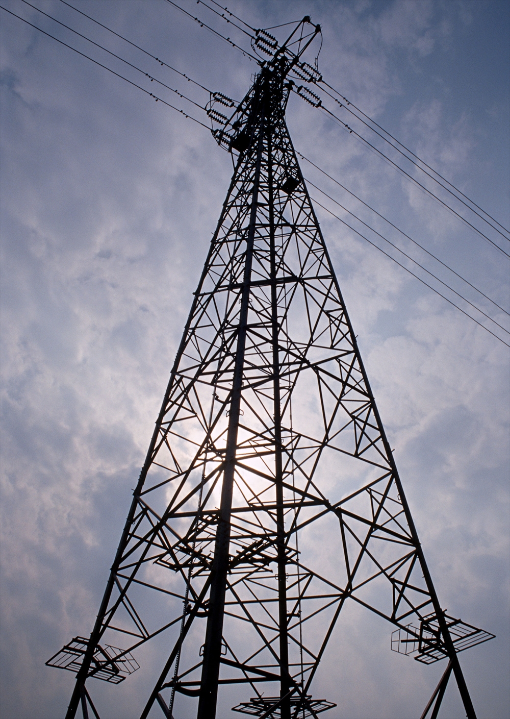 IMAGE_これは電力線の鉄塔の写真です。鉄塔は上空の高圧電線を支えるための構造物で、電力の送電に使用されます。バックグラウンドには曇り空が写っています。