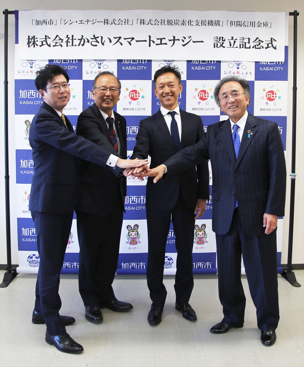 加西市 地域エネルギー会社設立 脱炭素化支援機構も出資_設立記念式で手を重ねる4者。(左から)脱炭素化支援機構・熊倉基之取締役常務執行役員、高橋市長、シン・エナジー・乾正博代表取締役社長、但陽信用金庫・桑田純一郎理事長