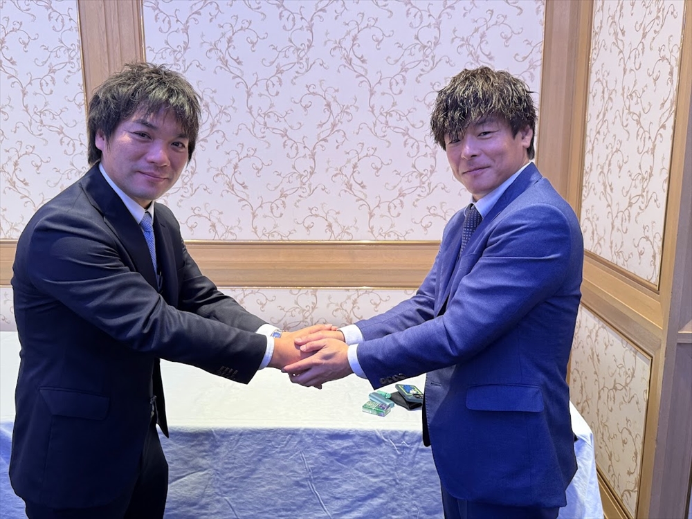 握手する上村会長（右）と天野実行委員長