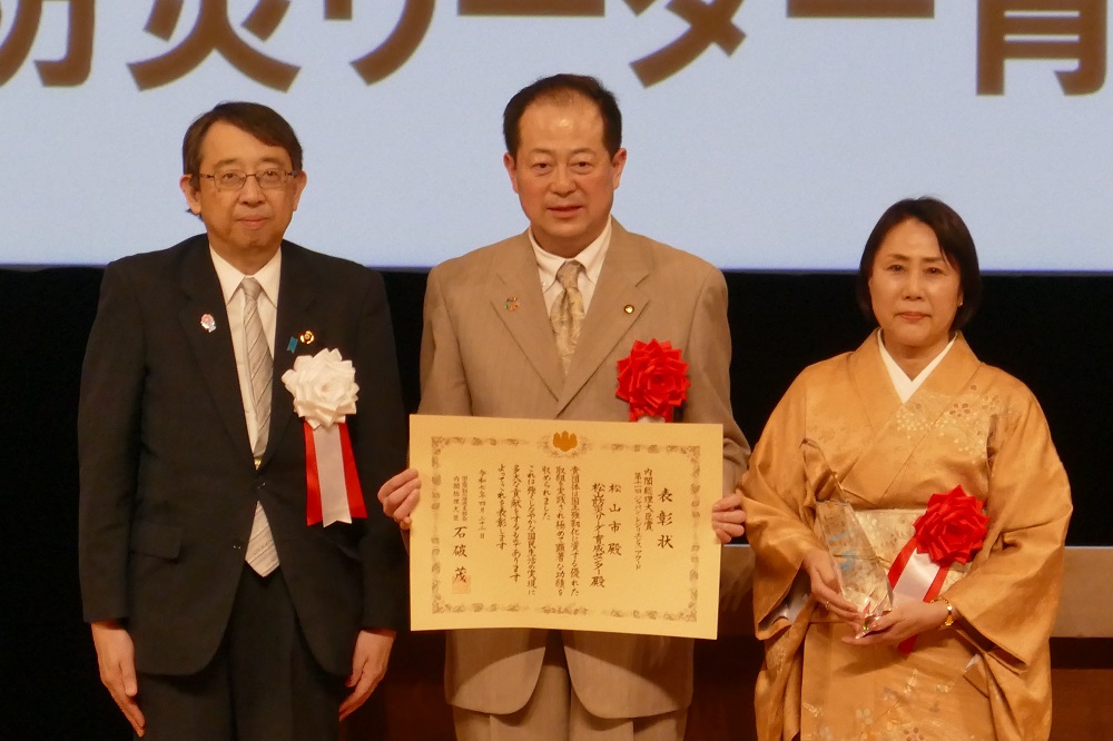 左から橘慶一郎内閣官房副長官と松山市、松山防災リーダー育成センター