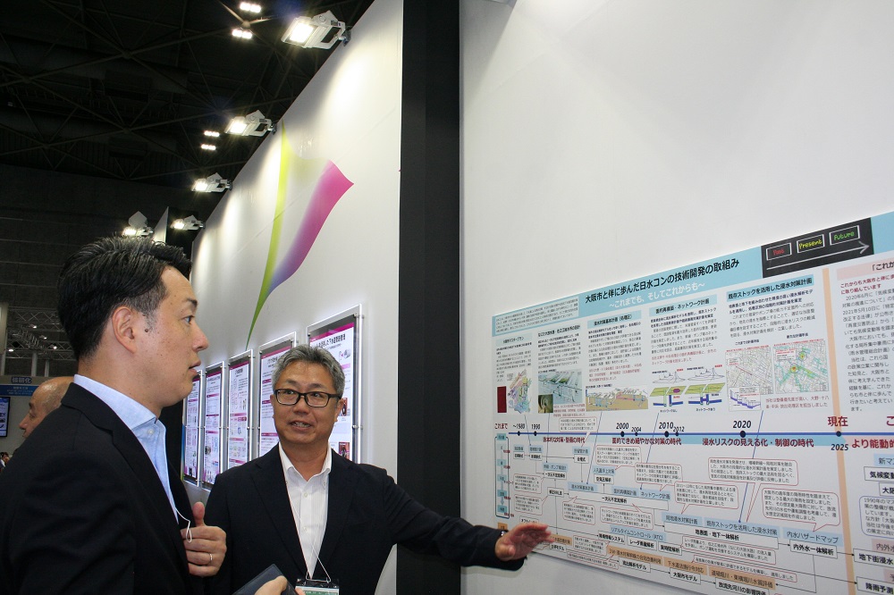 「下水道展'25大阪」　下水道の課題解決へ技術・機器が一堂に　管路点検・調査や官民連携など幅広く_出展者の説明に熱心に耳を傾ける横山英幸大阪市長（左）