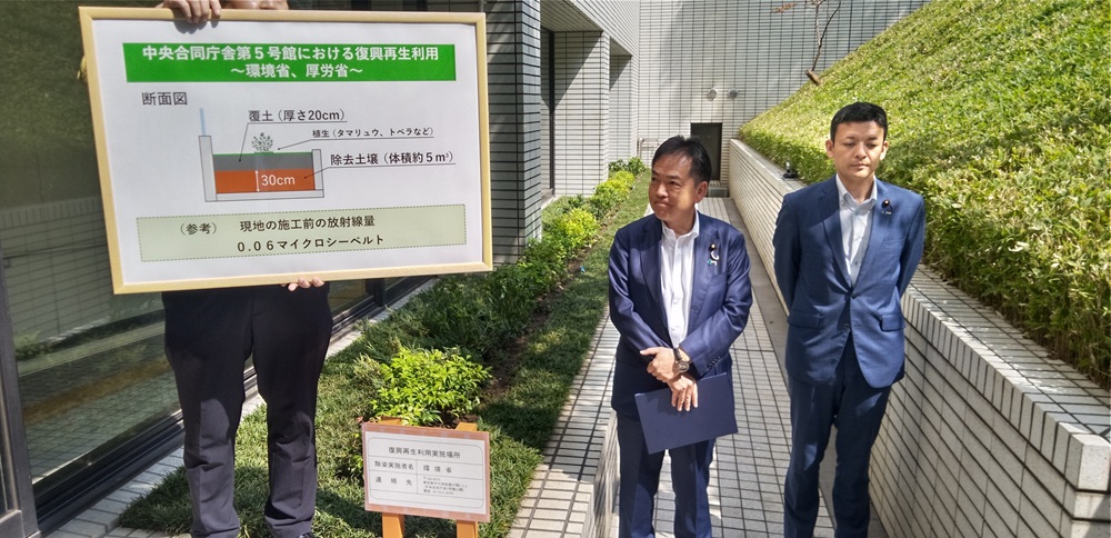 公取委 軽油カルテル疑いで強制調査　補助金効果を削減 運送業者に打撃　軽油の暫定税率 与野党協議に影響_花壇の上に掲げられたパネルで安全性を説明する浅尾環境相（左）と吉田真次厚労政務官