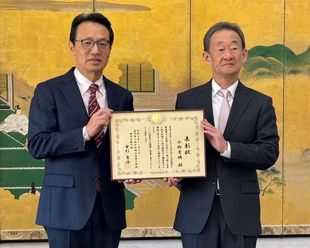 シャオリュウの中国環境ウオッチ（144）　地球環境戦略研究機関（IGES）北京事務所所長 小柳秀明　４中全会・第15次５カ年計画の建議_11月３日、金杉憲治大使（左）から表彰を受ける筆者