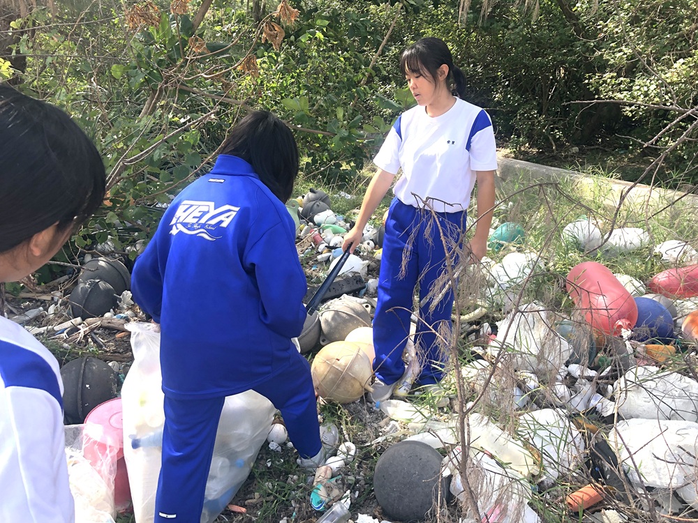 海外からの漂着ごみが散乱する海岸を住民と清掃する生徒