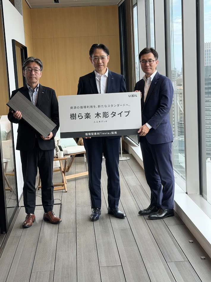 同社本社での記者発表に臨んだ吉田聡執行役専務（中央）ら。床には「樹ら楽 木彫タイプ」が使用されている