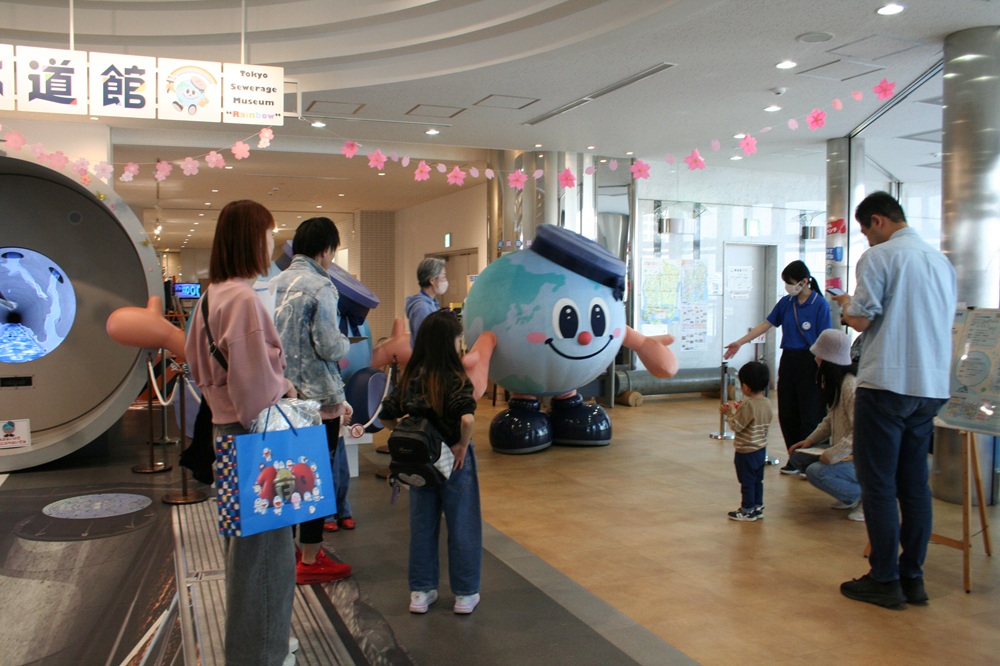 今年３月に虹の下水道管で行われたイベントの様子。写真中央は公式キャラクターの「アースくん」。誕生25周年を記念してデザインをリニューアル